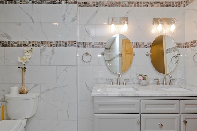 bathroom with vanity, toilet, and tile walls