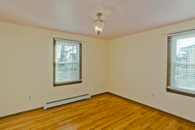 unfurnished room with plenty of natural light, light hardwood / wood-style floors, and a baseboard heating unit