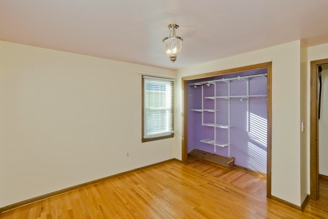 unfurnished bedroom featuring hardwood / wood-style floors, a chandelier, and a closet