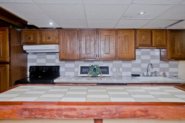 kitchen with sink, tasteful backsplash, tile countertops, a paneled ceiling, and black range