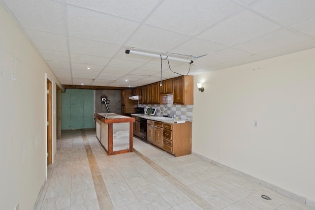 kitchen featuring a drop ceiling, sink, a center island, hanging light fixtures, and black dishwasher