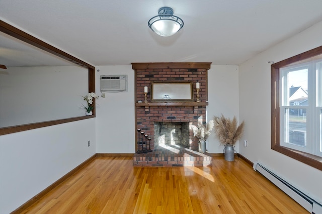 unfurnished living room featuring light wood-type flooring, a fireplace, a wall mounted AC, and a baseboard heating unit