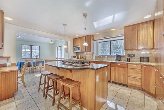 kitchen with light tile patterned floors, appliances with stainless steel finishes, a kitchen island, and pendant lighting