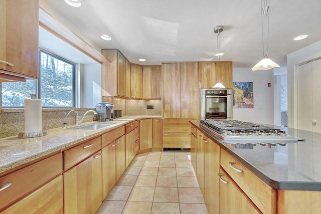 kitchen featuring light stone counters, a sink, appliances with stainless steel finishes, decorative backsplash, and pendant lighting