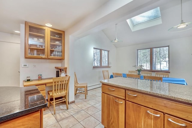 kitchen featuring decorative light fixtures, glass insert cabinets, a baseboard heating unit, light stone countertops, and plenty of natural light