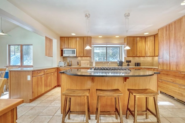 kitchen featuring decorative backsplash, a center island, a peninsula, stainless steel appliances, and light tile patterned flooring