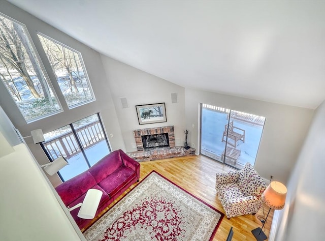 living area featuring a healthy amount of sunlight, a brick fireplace, visible vents, and wood finished floors