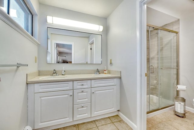 full bath featuring double vanity, a stall shower, and a sink