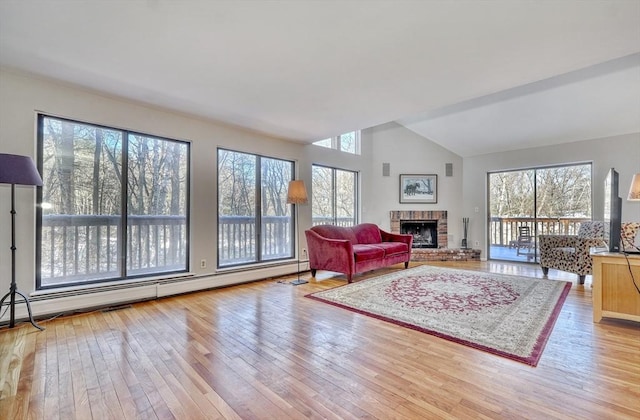 living room with light wood-style flooring, a fireplace, a baseboard heating unit, and a wealth of natural light