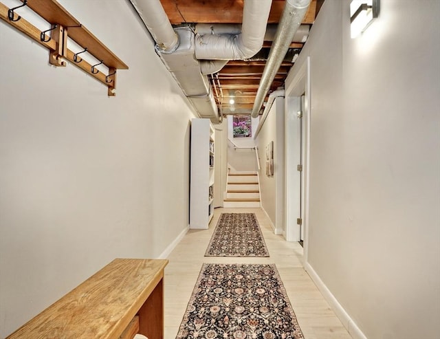 corridor featuring light wood finished floors, stairs, and baseboards