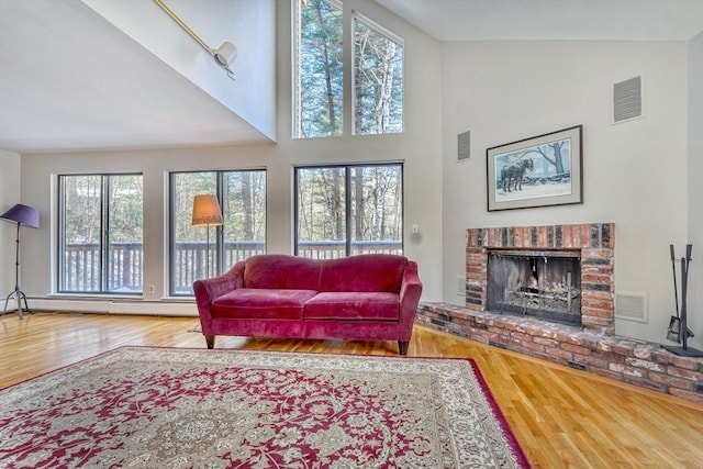 living area with a fireplace, visible vents, and wood finished floors