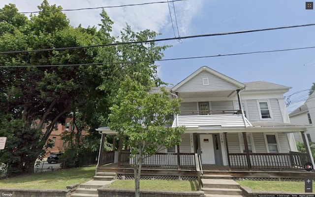 view of front of home with a balcony, a porch, and a front yard