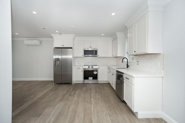 kitchen with baseboards, a wall mounted air conditioner, light wood-style floors, a sink, and stainless steel appliances