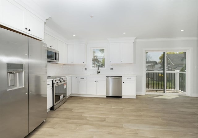 kitchen featuring appliances with stainless steel finishes, ornamental molding, a sink, and plenty of natural light