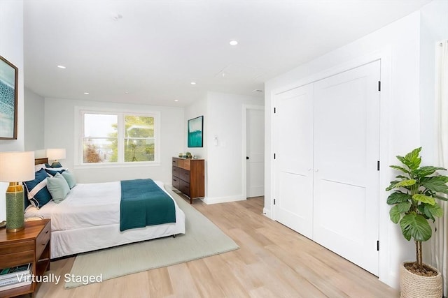 bedroom with recessed lighting, baseboards, light wood-style flooring, and a closet