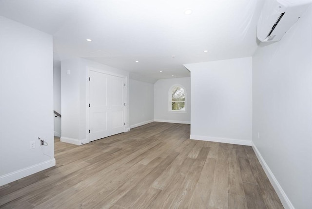 spare room featuring light wood-type flooring, recessed lighting, baseboards, and a wall unit AC