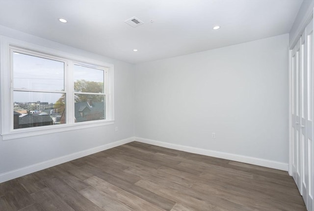 empty room with baseboards, recessed lighting, wood finished floors, and visible vents