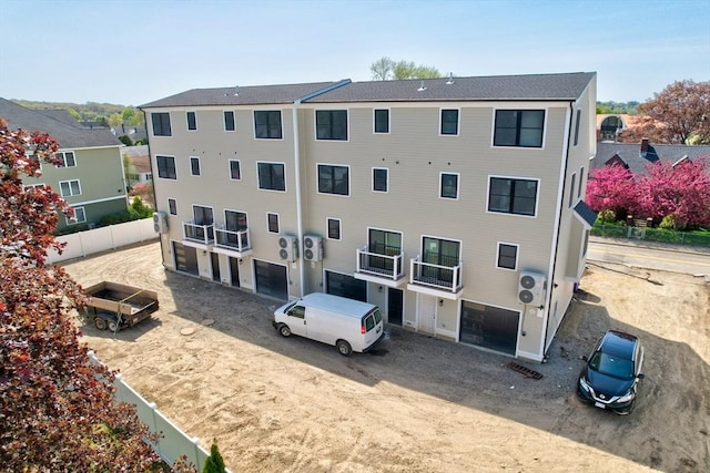 view of building exterior featuring dirt driveway, fence, and a garage