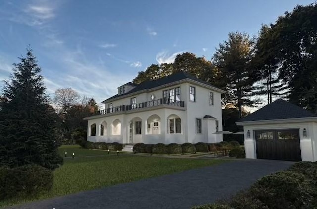 view of front of house featuring a garage, a lawn, and a balcony