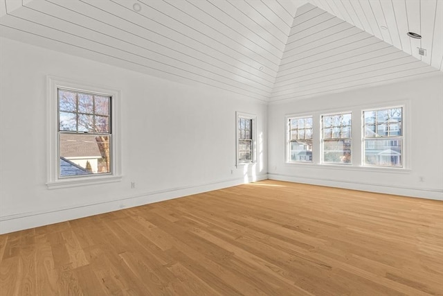 unfurnished living room featuring lofted ceiling, a wealth of natural light, and light hardwood / wood-style floors