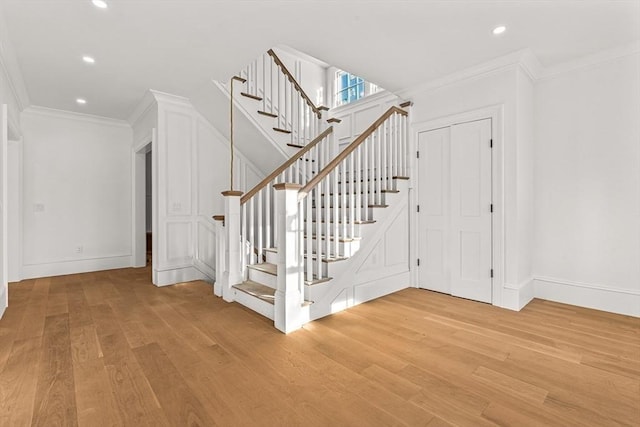 stairs featuring crown molding and hardwood / wood-style floors