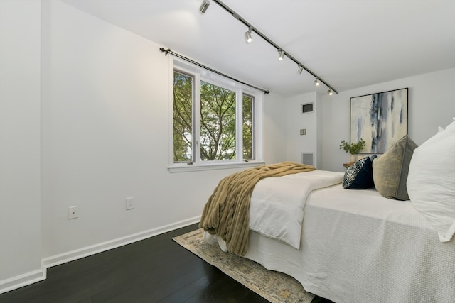 bedroom featuring rail lighting and dark hardwood / wood-style flooring