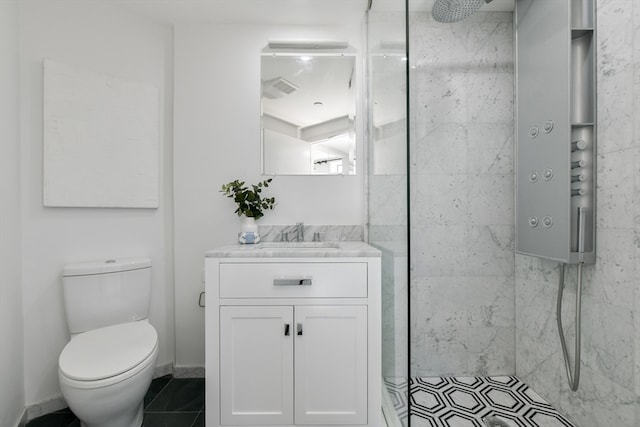 bathroom with tile patterned flooring, toilet, vanity, and tiled shower