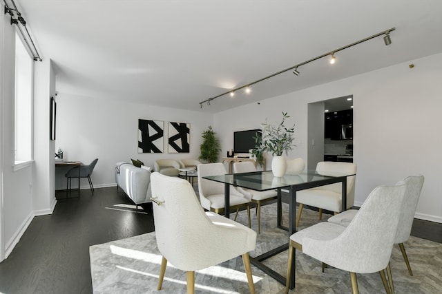 dining area featuring dark wood-type flooring and track lighting