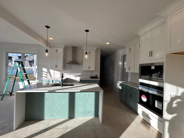 kitchen with pendant lighting, sink, stainless steel appliances, white cabinets, and wall chimney exhaust hood