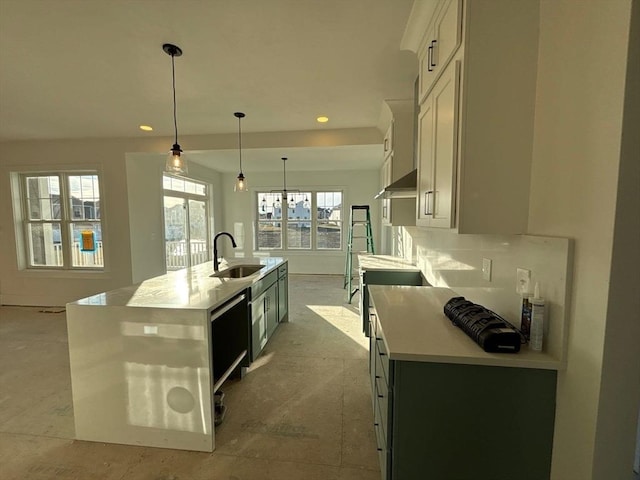 kitchen featuring sink, decorative light fixtures, dishwasher, and an island with sink