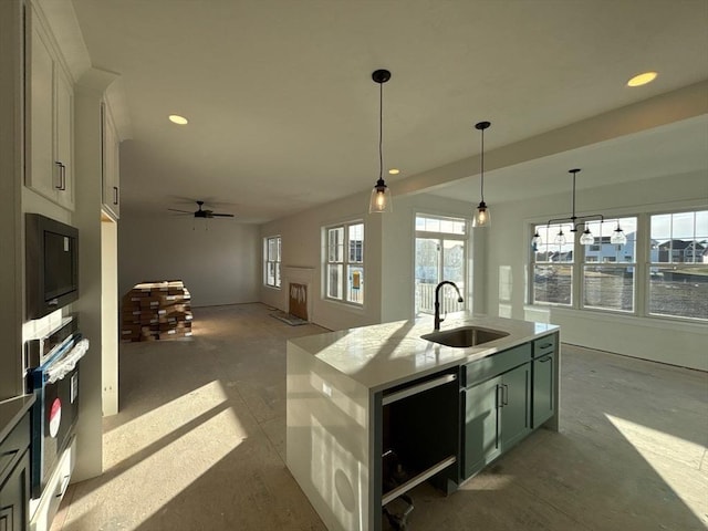 kitchen featuring sink, a kitchen island with sink, white cabinetry, hanging light fixtures, and oven