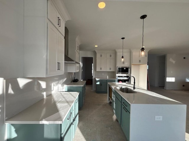 kitchen featuring appliances with stainless steel finishes, decorative light fixtures, an island with sink, white cabinets, and wall chimney range hood