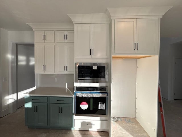 kitchen with stainless steel appliances, dark tile patterned floors, and white cabinets