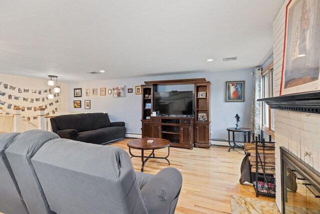 11 Michael Rd, Bourne, MA 02559 - living area featuring light wood finished floors, visible vents, a baseboard heating unit, a fireplace, and baseboard heating