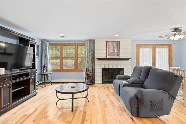 11 Michael Rd, Bourne, MA 02559 - living room featuring a baseboard heating unit, ceiling fan, a brick fireplace, and light wood-style floors