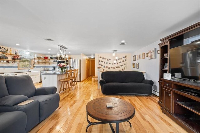 11 Michael Rd, Bourne, MA 02559 - living room featuring a baseboard radiator, visible vents, light wood finished floors, and an inviting chandelier