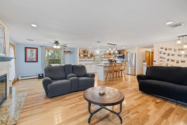 11 Michael Rd, Bourne, MA 02559 - living area featuring baseboard heating, light wood finished floors, a premium fireplace, visible vents, and recessed lighting