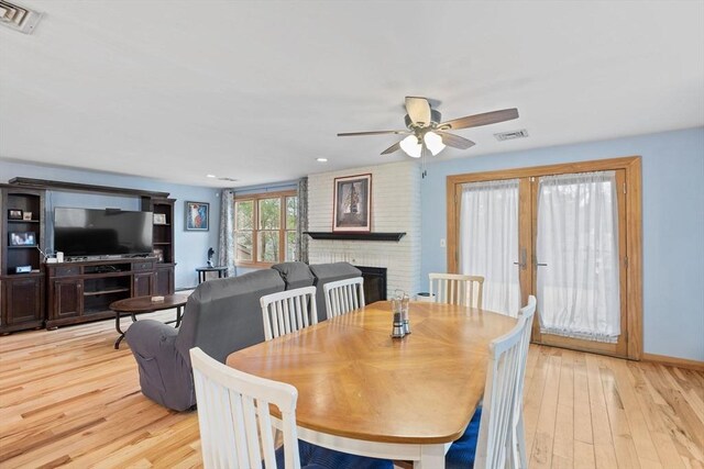 11 Michael Rd, Bourne, MA 02559 - dining room with a fireplace, light wood-style flooring, visible vents, and ceiling fan