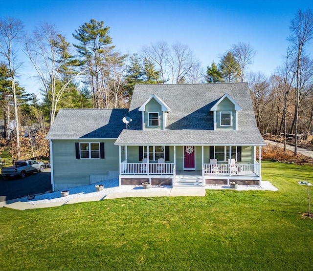 new england style home with covered porch, a front lawn, and roof with shingles