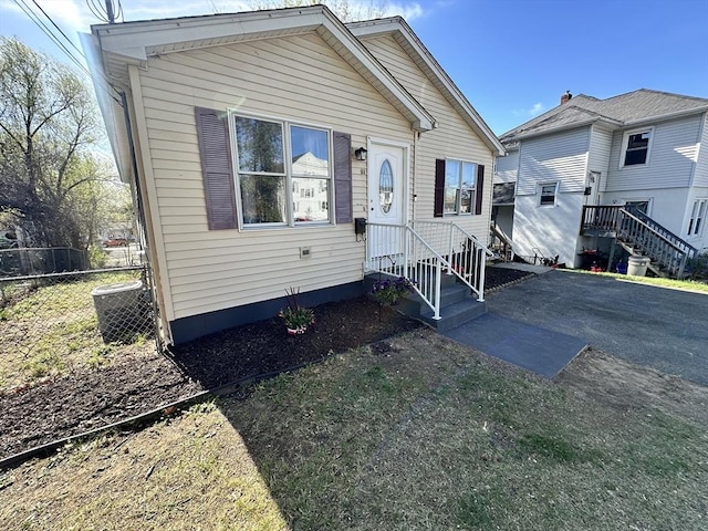 bungalow featuring central AC unit and fence