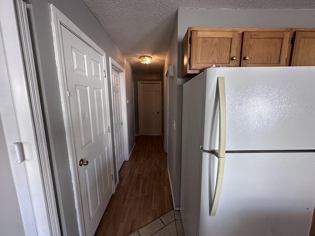 corridor with a textured ceiling and tile patterned flooring