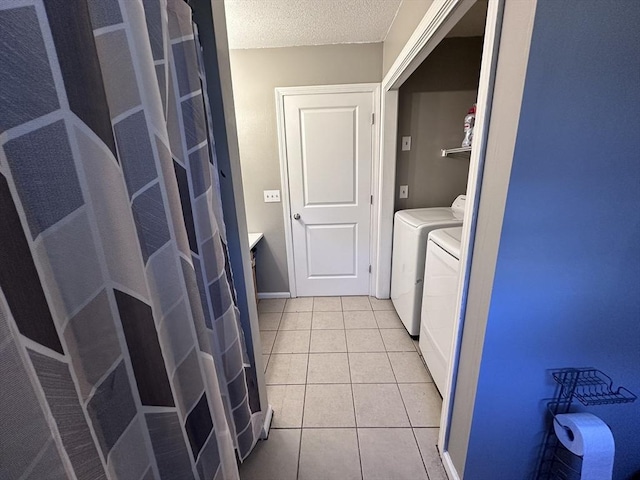 clothes washing area with light tile patterned floors, a textured ceiling, laundry area, and independent washer and dryer