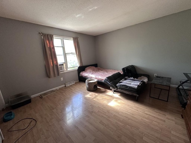 bedroom featuring cooling unit, a textured ceiling, baseboards, wood finished floors, and visible vents