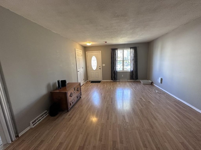 entryway featuring baseboards, a textured ceiling, visible vents, and wood finished floors