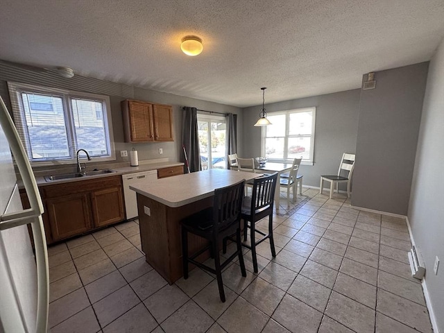 kitchen with freestanding refrigerator, white dishwasher, light tile patterned floors, and a sink