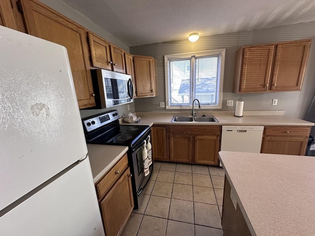 kitchen with a sink, light countertops, stainless steel appliances, and light tile patterned flooring