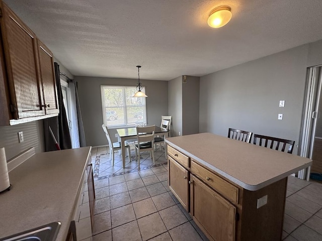 kitchen featuring light countertops, a textured ceiling, light tile patterned floors, and a kitchen island