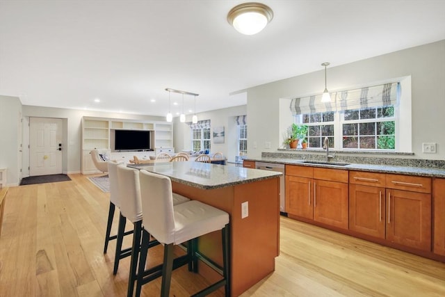 kitchen with light stone countertops, a center island, decorative light fixtures, and sink