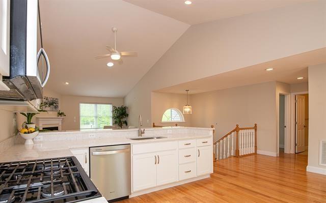41 Winchester Unit 0, Hampstead, NH 03826 - kitchen with stainless steel dishwasher, a sink, white cabinets, a fireplace, and light wood-style floors