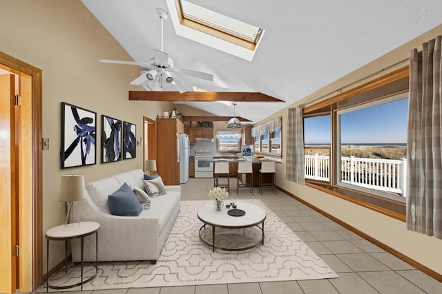 living room featuring a skylight, ceiling fan, light tile patterned floors, and high vaulted ceiling